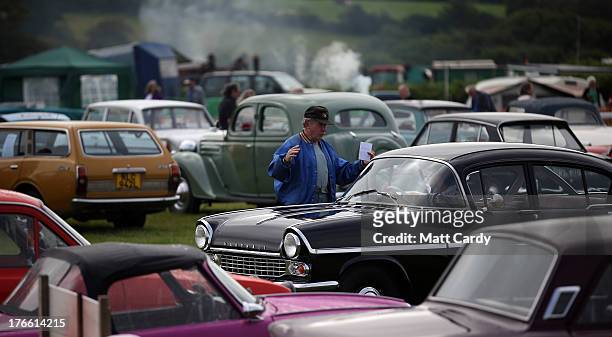 People gather around classic cars being shown in the showground at the Cornish Steam and Country Fair at the Stithians Showground on August 16, 2013...
