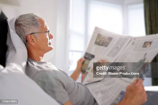 mature man reading a newspaper in bed - read and newspaper and bed stock pictures, royalty-free photos & images