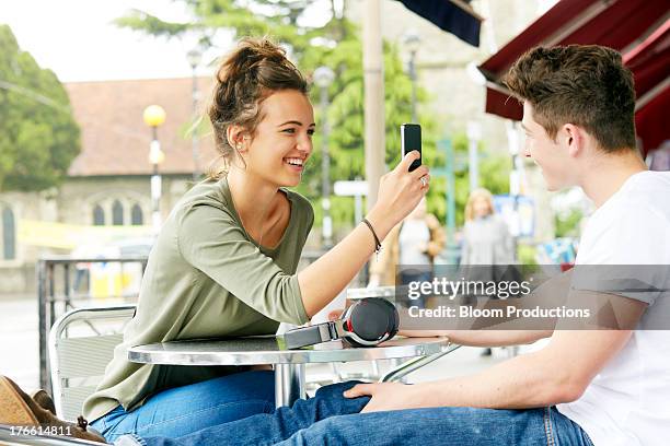 teenager taking a photo of friend on a smart phone - boy girl stock pictures, royalty-free photos & images