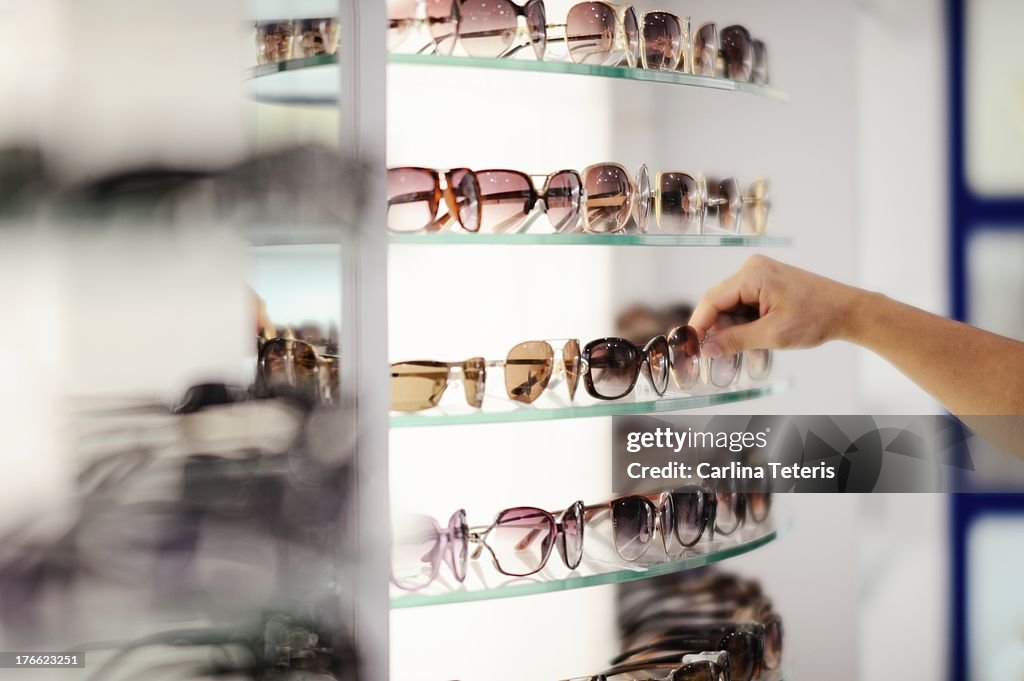 Hand picking out sunglasses from a store shelf