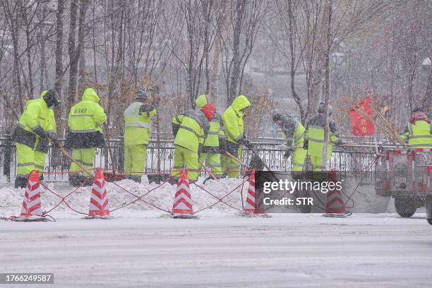 Workers clean up a street during snowfall in Harbin, in China's northeastern Heilongjiang province on November 6, 2023. / China OUT