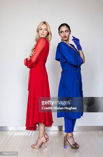 two beautiful young woman standing back to back - blue dress stock pictures, royalty-free photos & images