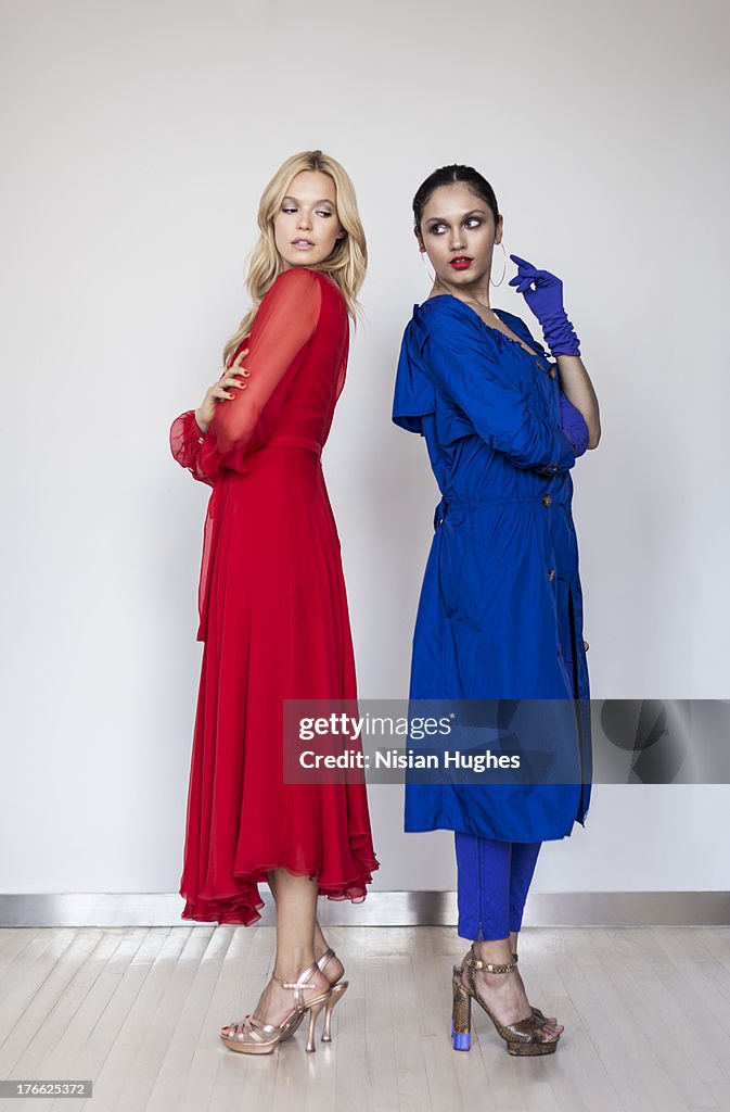 Two beautiful young woman standing back to back