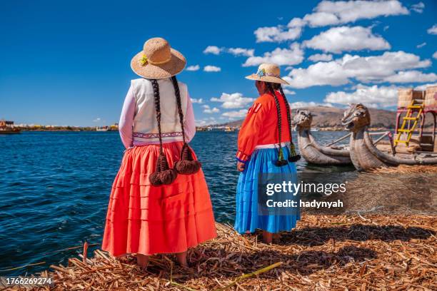 dos mujeres peruanas en la isla flotante de los uros, el lago tititcaca - quechuas fotografías e imágenes de stock