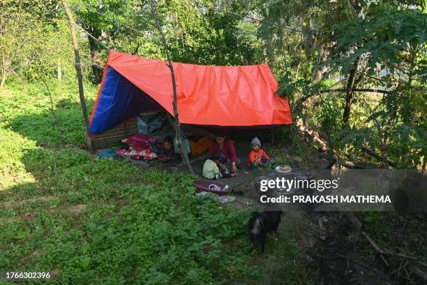 People sit inside a makeshift shelter following a earthquake in Khalanga of Jajarkot district on November 6, 2023. At least 157 people were killed in...