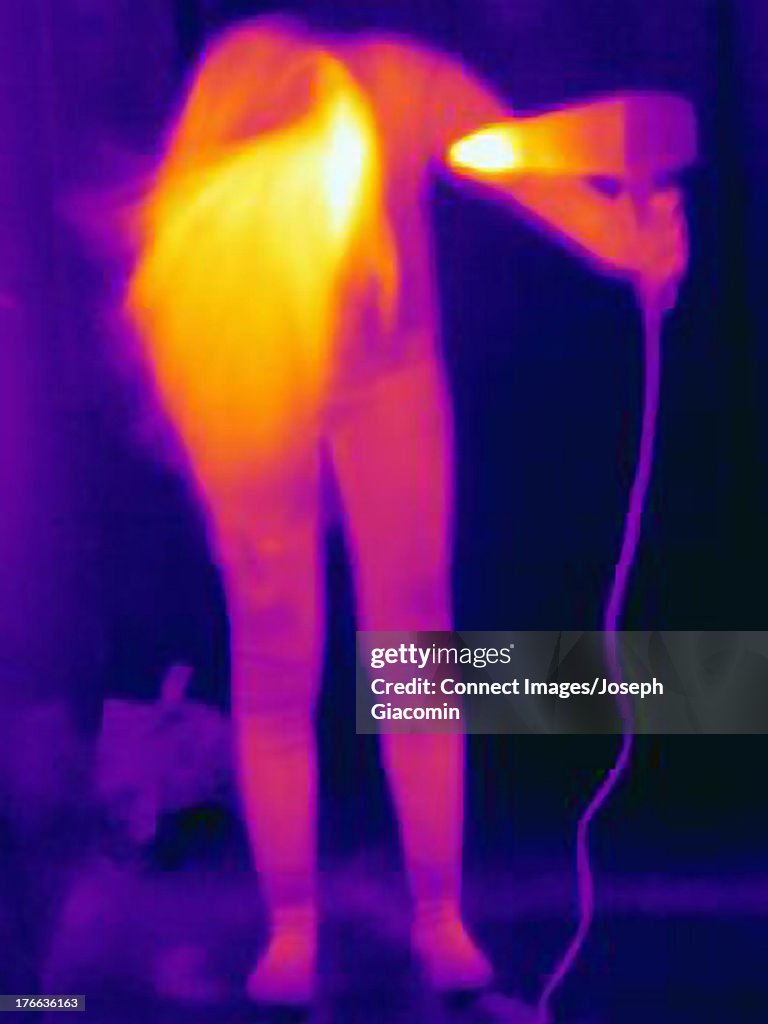 Thermal image of young woman drying her hair