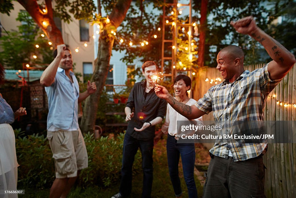 Man dancing and holding sparklers at garden party