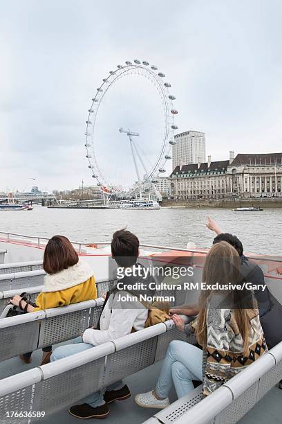 tourists on riverboat looking at london eye - millennium wheel stockfoto's en -beelden