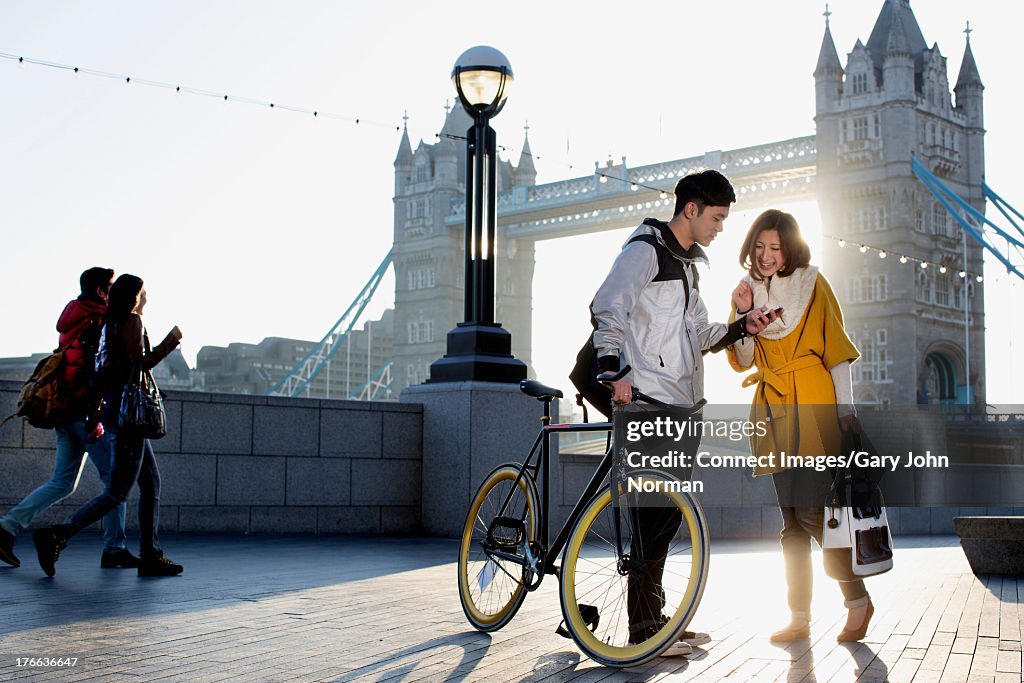 Young man holding bicycle with woman at Tower Bridge, London, England