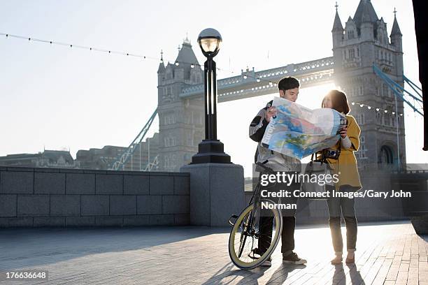 young couple reading map by tower bridge, london, england - london street map ストックフォトと画像