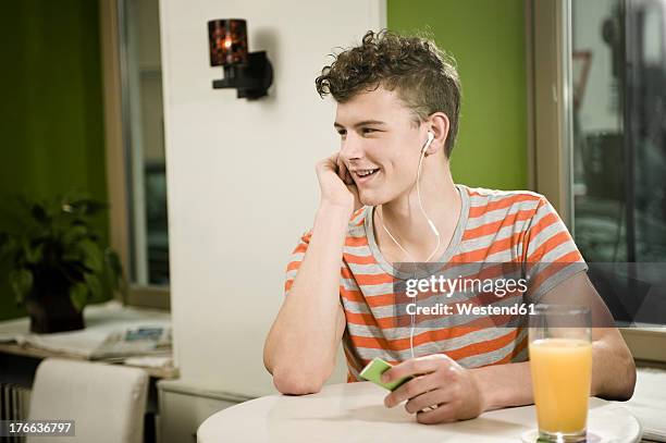 germany, bavaria, munich, young man listening music in cafe, smiling - mp3 juices 個照片及圖片檔