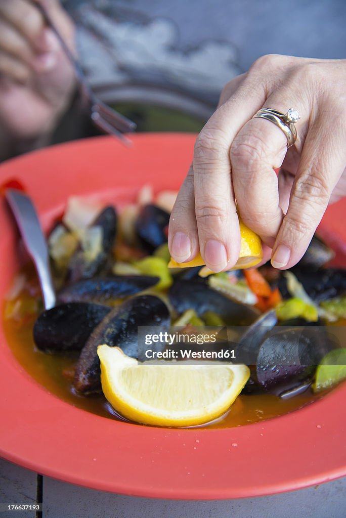 USA, Texas, Mature woman enjoying mussels dish in restaurant, close up