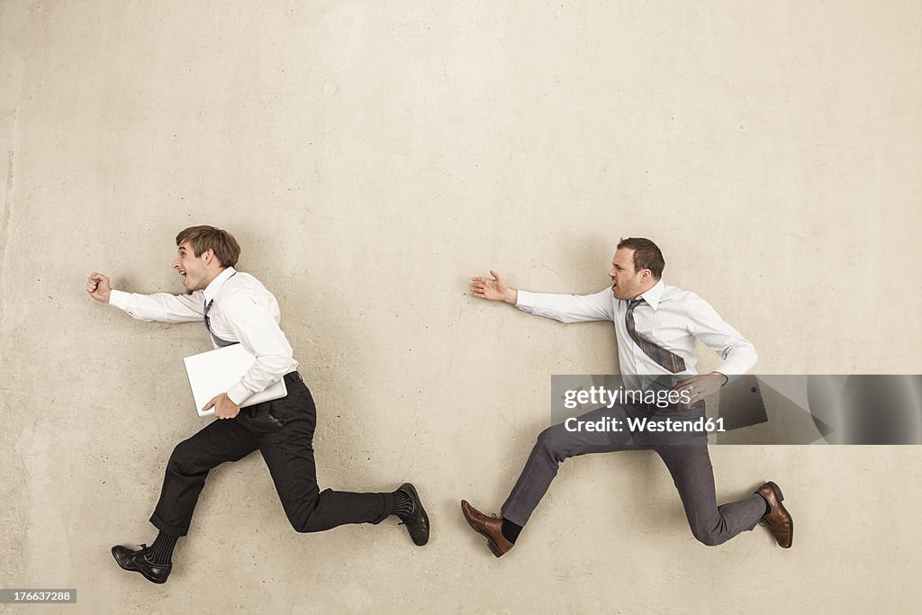 Businessmen chasing against beige background