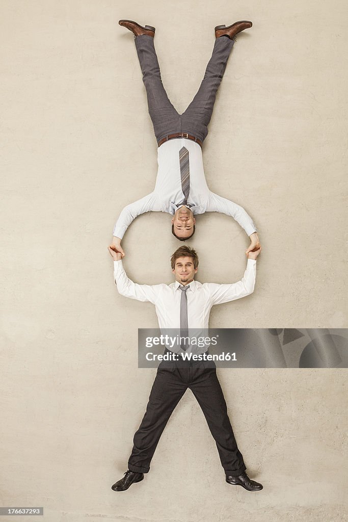 Businessmen with head to head position and holding hands against beige background