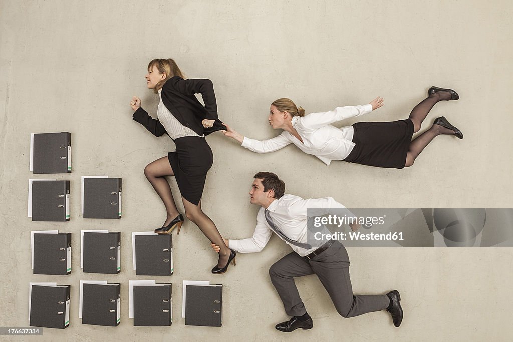 Businesswoman on staircase of files while others chasing