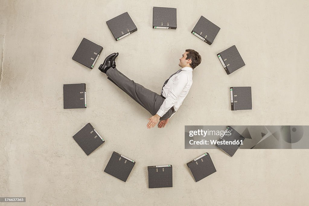Businessman inside circle of files forming clock