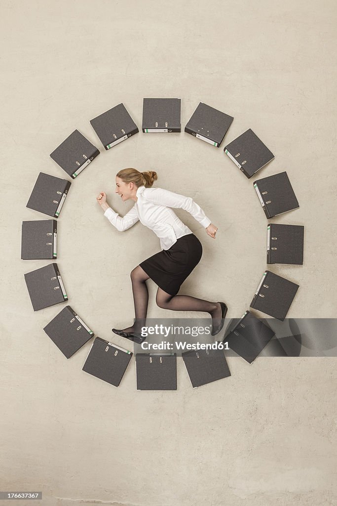 Businesswoman inside circle of files forming clock