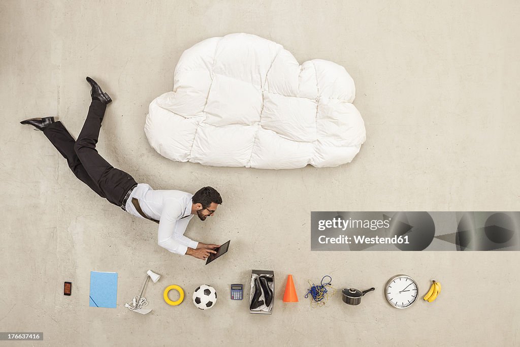 Businessman flying between cloud shape pillow and variety of items