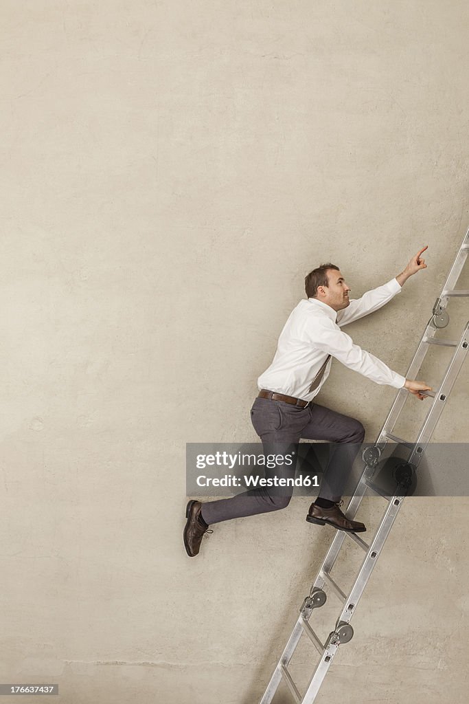 Businessman climbing ladder in office