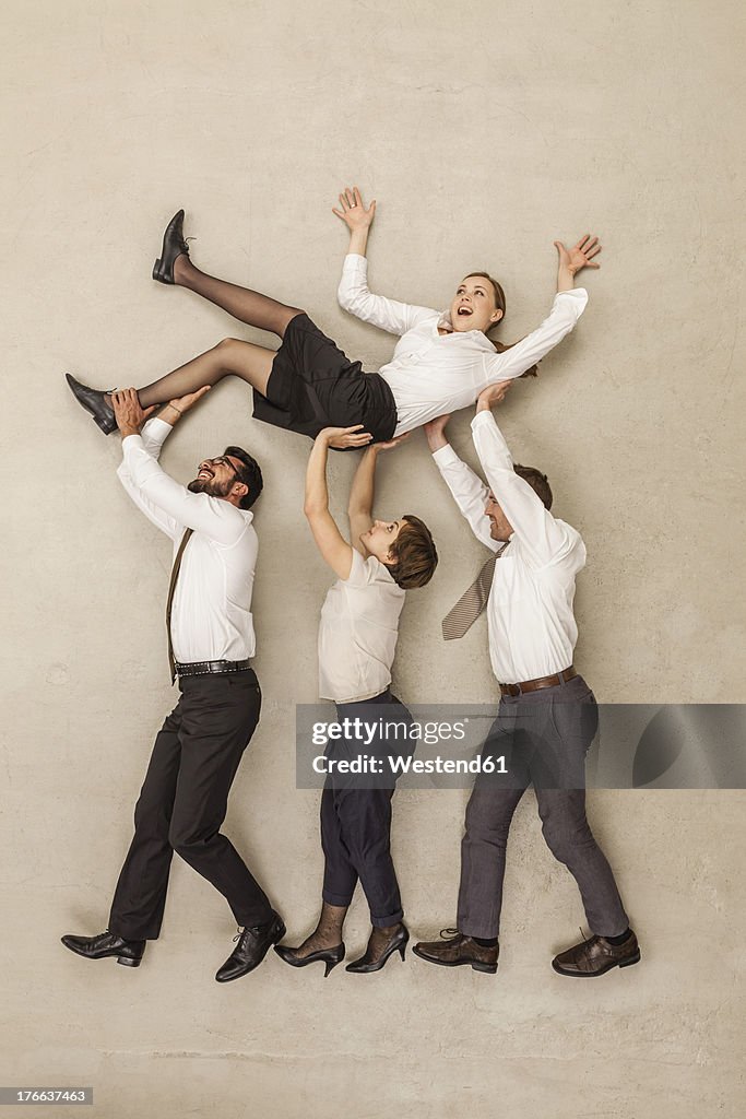 Business people carrying businesswoman in office