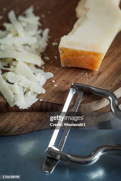 shredded parmesan with peeler on chopping board, close up - hartkäse stock-fotos und bilder