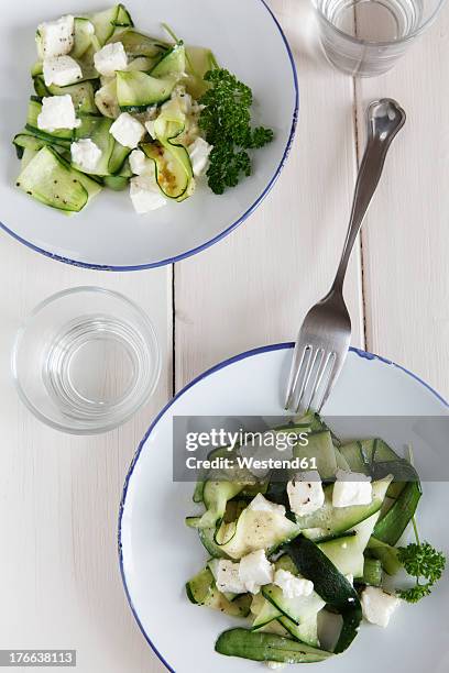 plate of salad with zucchini, feta cheese and parsley on wooden table - feta stock pictures, royalty-free photos & images