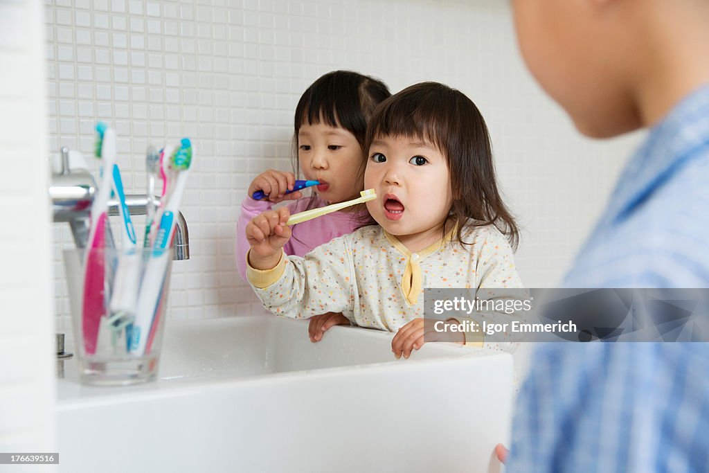 Two girls brushing teeth at bathroom sink