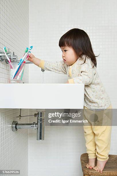 girl toddler on tiptoe reaching over bathroom sink - tiptoe stock-fotos und bilder