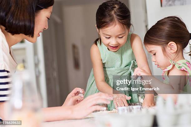 mother and young daughters making pastry - mother daughter baking stock pictures, royalty-free photos & images