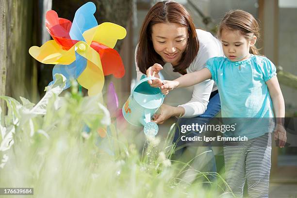 mother and daughter with watering can and toy windmill - japanese people lesson english stock pictures, royalty-free photos & images