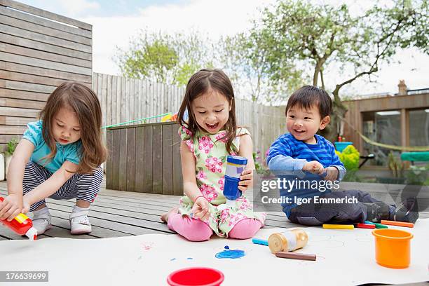 three young children painting and drawing in garden - cute japanese drawings stockfoto's en -beelden