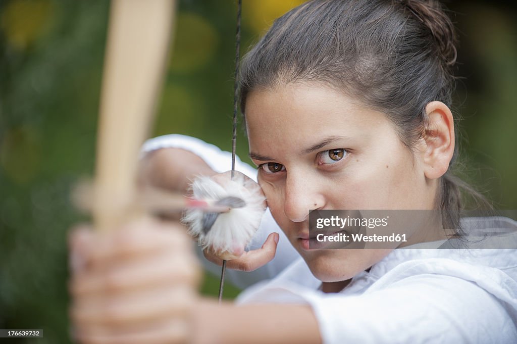 Austria, Salzburg Country, Young woman aiming arrow, close up