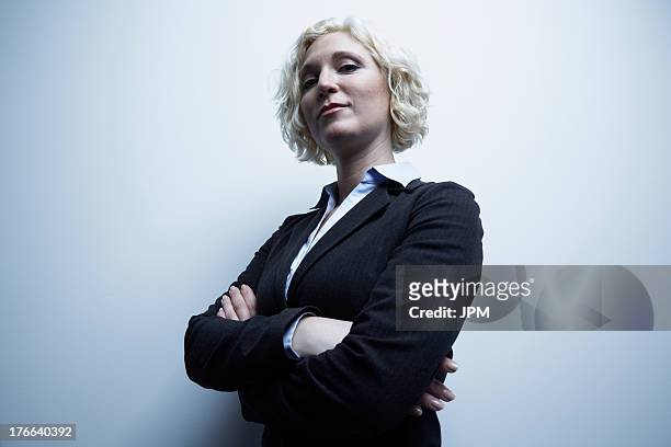 studio portrait of businesswoman with arms crossed - vantarsi foto e immagini stock