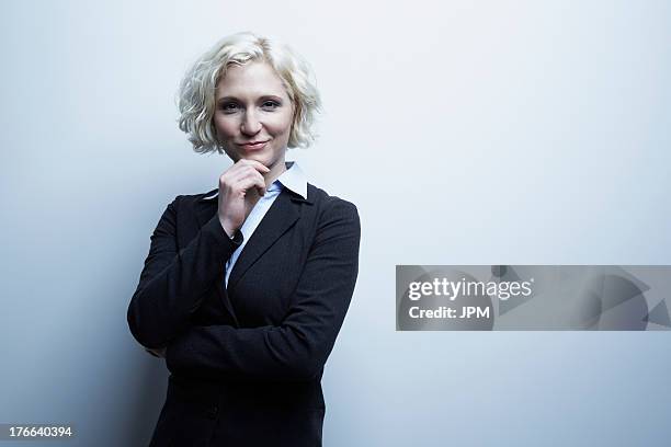 studio portrait of businesswoman with hand on chin - sourire narquois photos et images de collection
