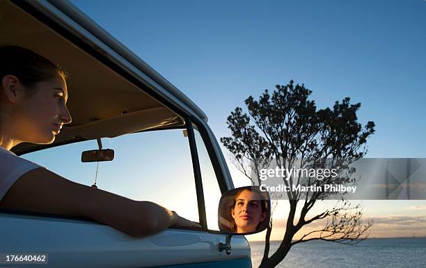 young woman looking out of camper van window at dusk - side mirror stock pictures, royalty-free photos & images