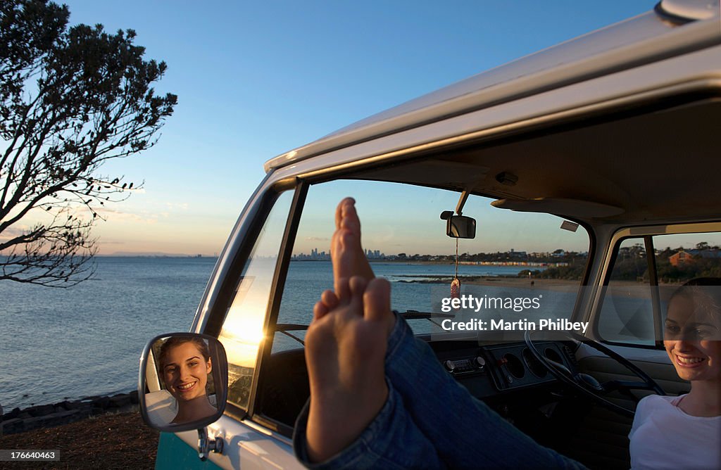 Young woman with feet up on camper van window