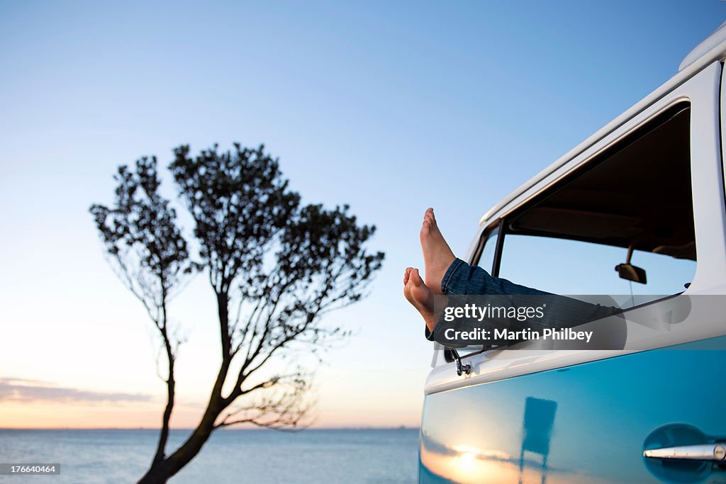 Feet out of camper van window at dusk