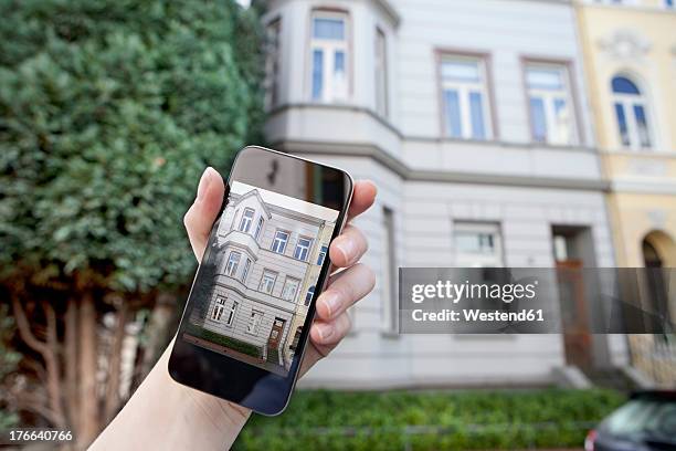 germany, bonn, human hand using smart phone in front of house - montezuma cypress stock pictures, royalty-free photos & images