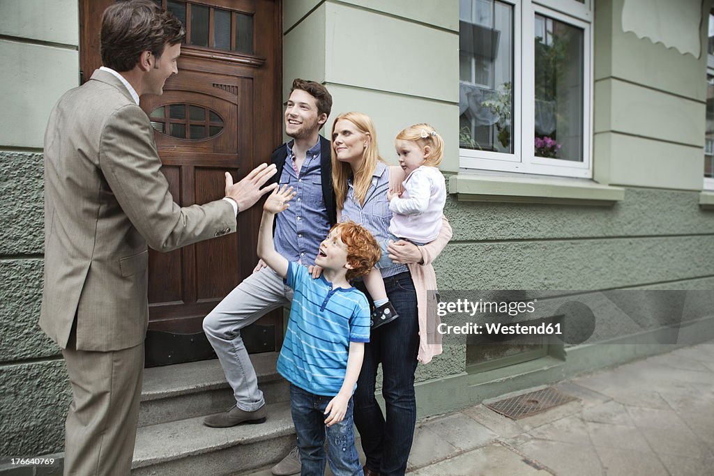 Germany, Duesseldorf, Boy giving high five to estate agent and family standing in background