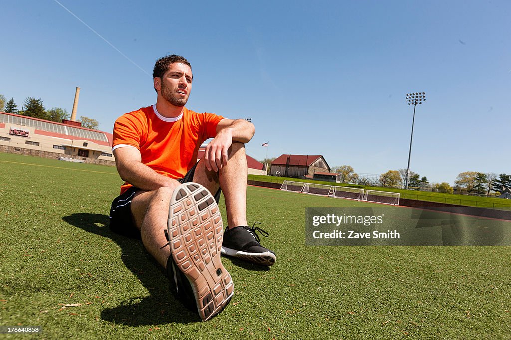 Young man taking a break on sport stadium grass