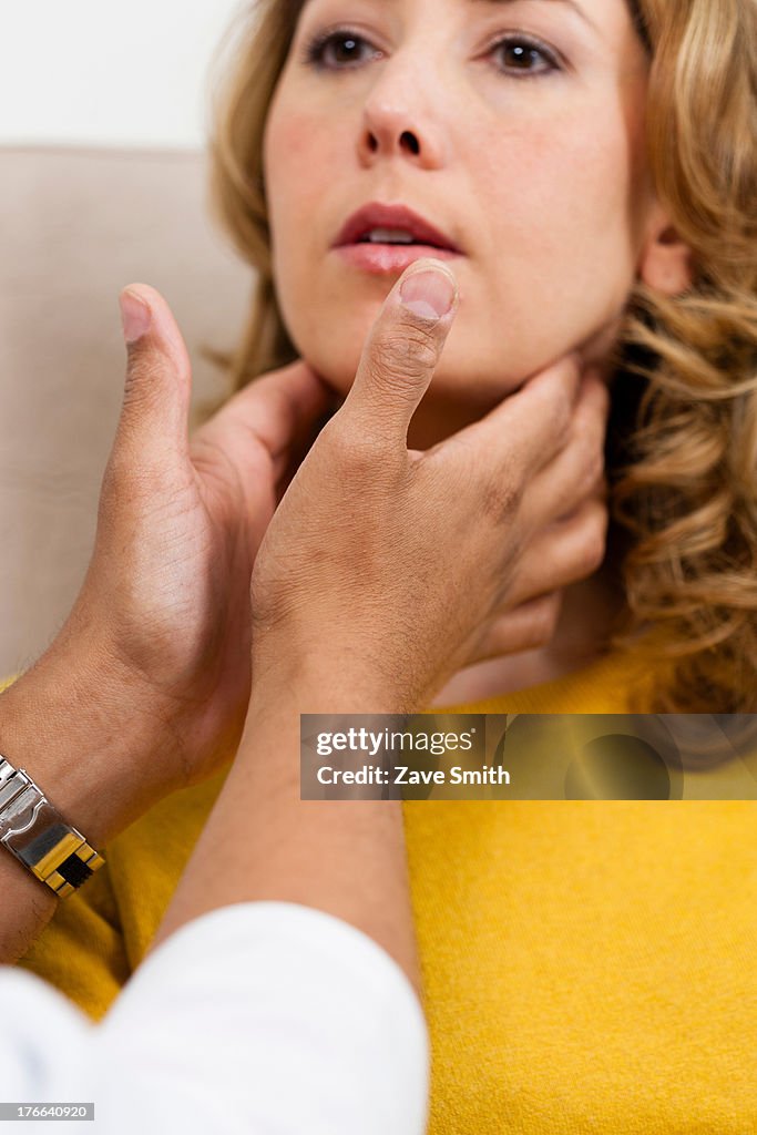 Doctor examining mid adult woman's throat, close up