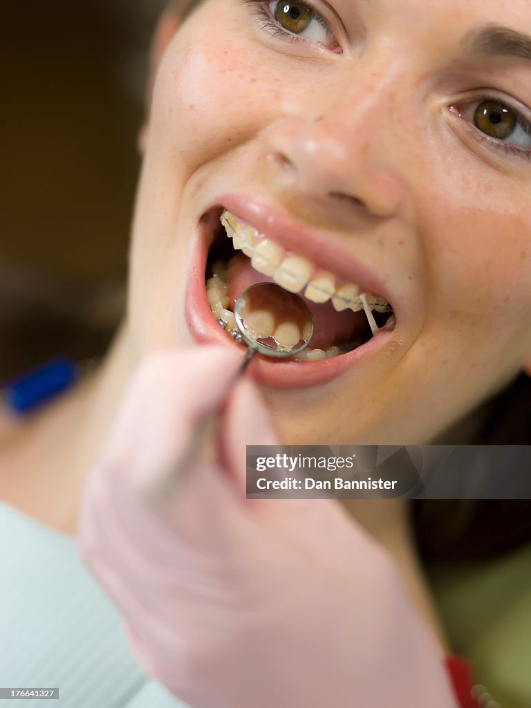 Dentist examining young woman's teeth, close up