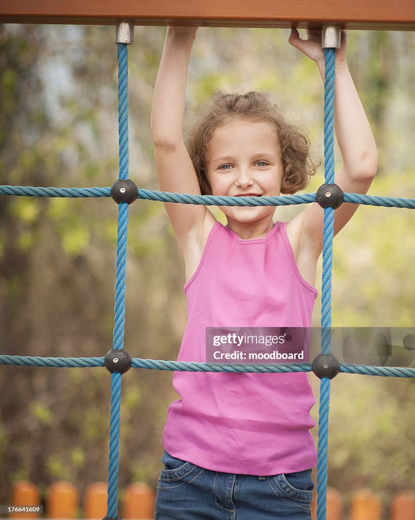 Half-length shot of young girl on climbing net