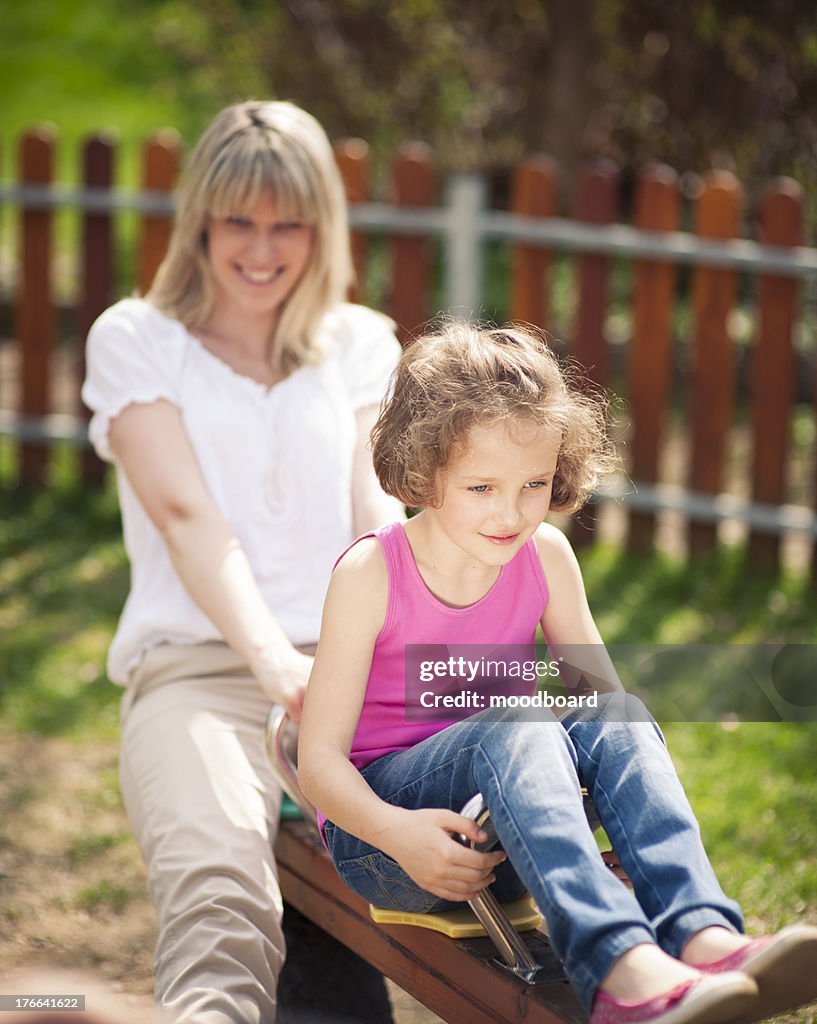Mother and daughter ride seesaw together