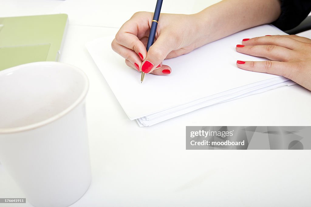 Close up of womans hands writing on paper.
