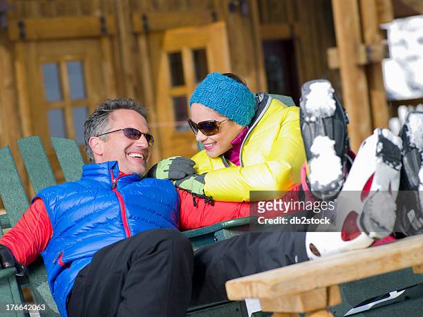 mature man and young woman relaxing together in ski resort - botas de après ski fotografías e imágenes de stock