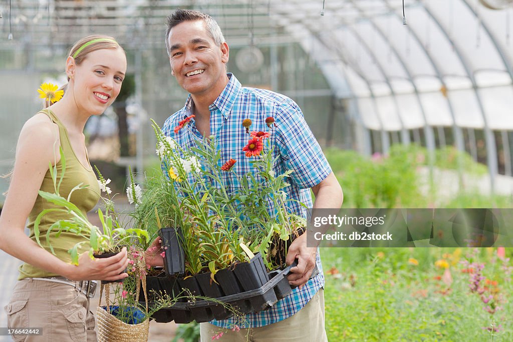 Mature man and mid adult woman shopping in garden centre, smiling