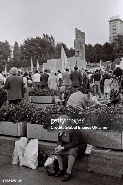 An elderly woman rests on a stone fence while the Ukrainian Popular Assembly participants gather under the fenced for demolition monument of the...