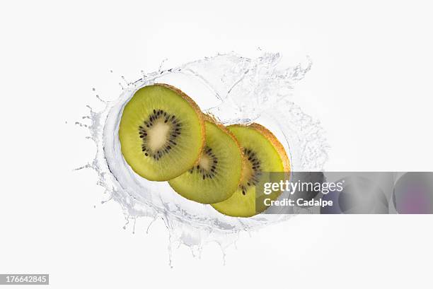 three slices of kiwi splashing in liquid - cadalpe stock pictures, royalty-free photos & images