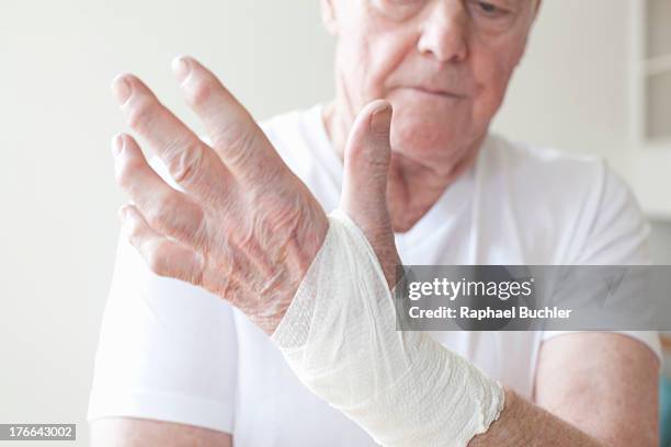 senior man with bandage on wrist - bandaged thumb stock pictures, royalty-free photos & images